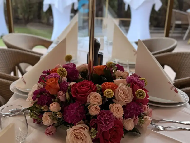 Gedeck mit Blumenschmuck auf einer Festtafel im Pavillon